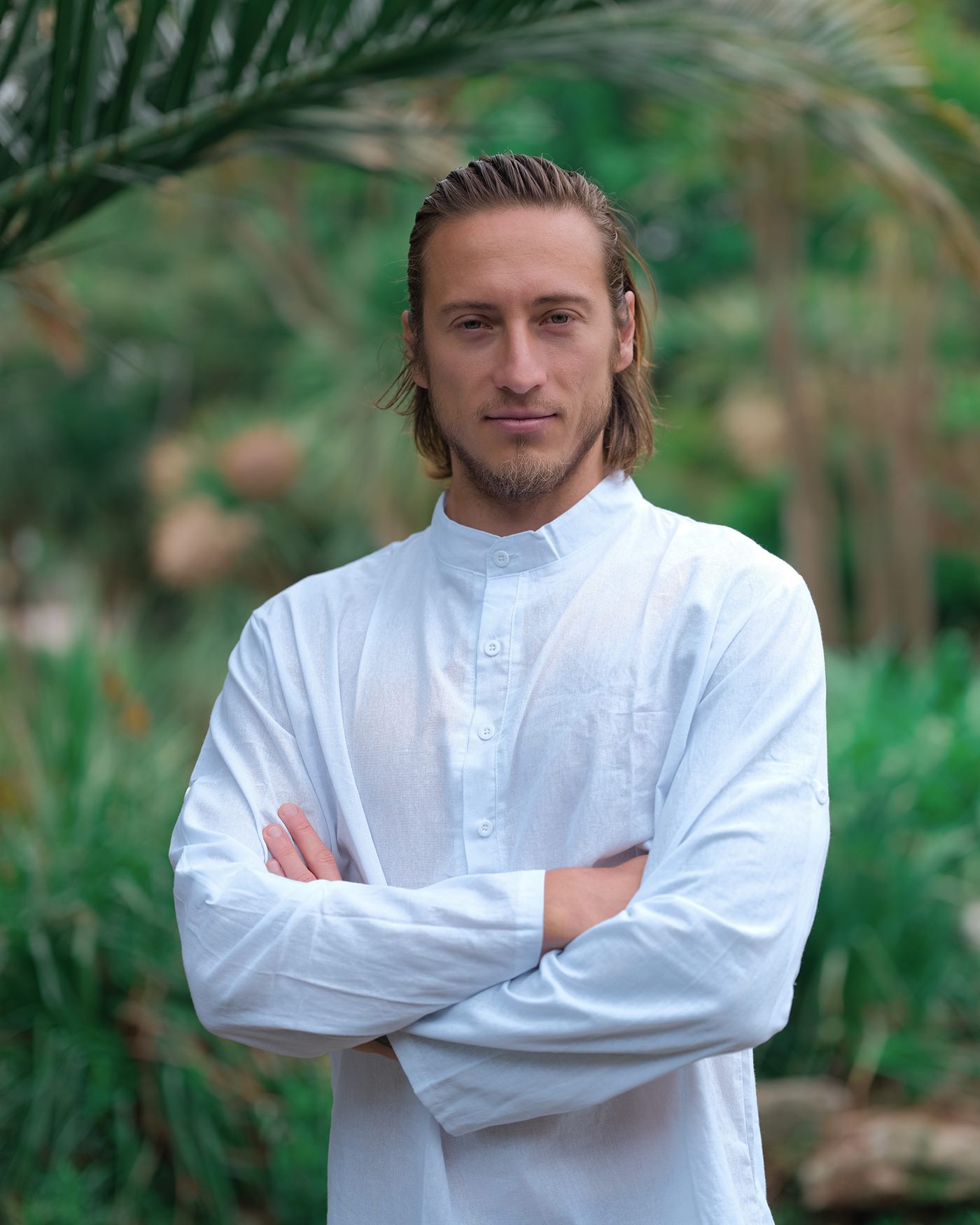 Karol, massage therapist in Bournemouth, standing in a garden wearing a white linen shirt
